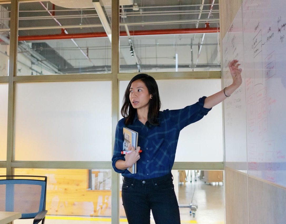 Clarizza arranging sticky notes on a whiteboard during an affinity mapping session