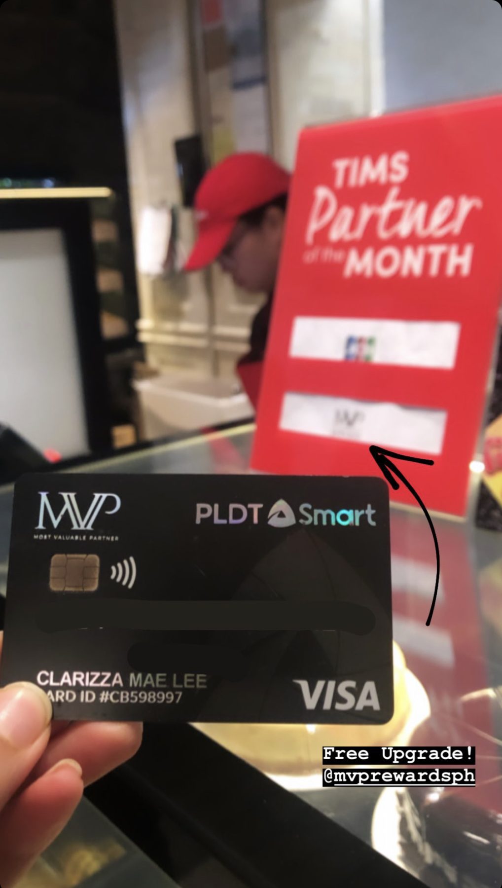 A hand holding a phone with MVP Rewards open at a café counter